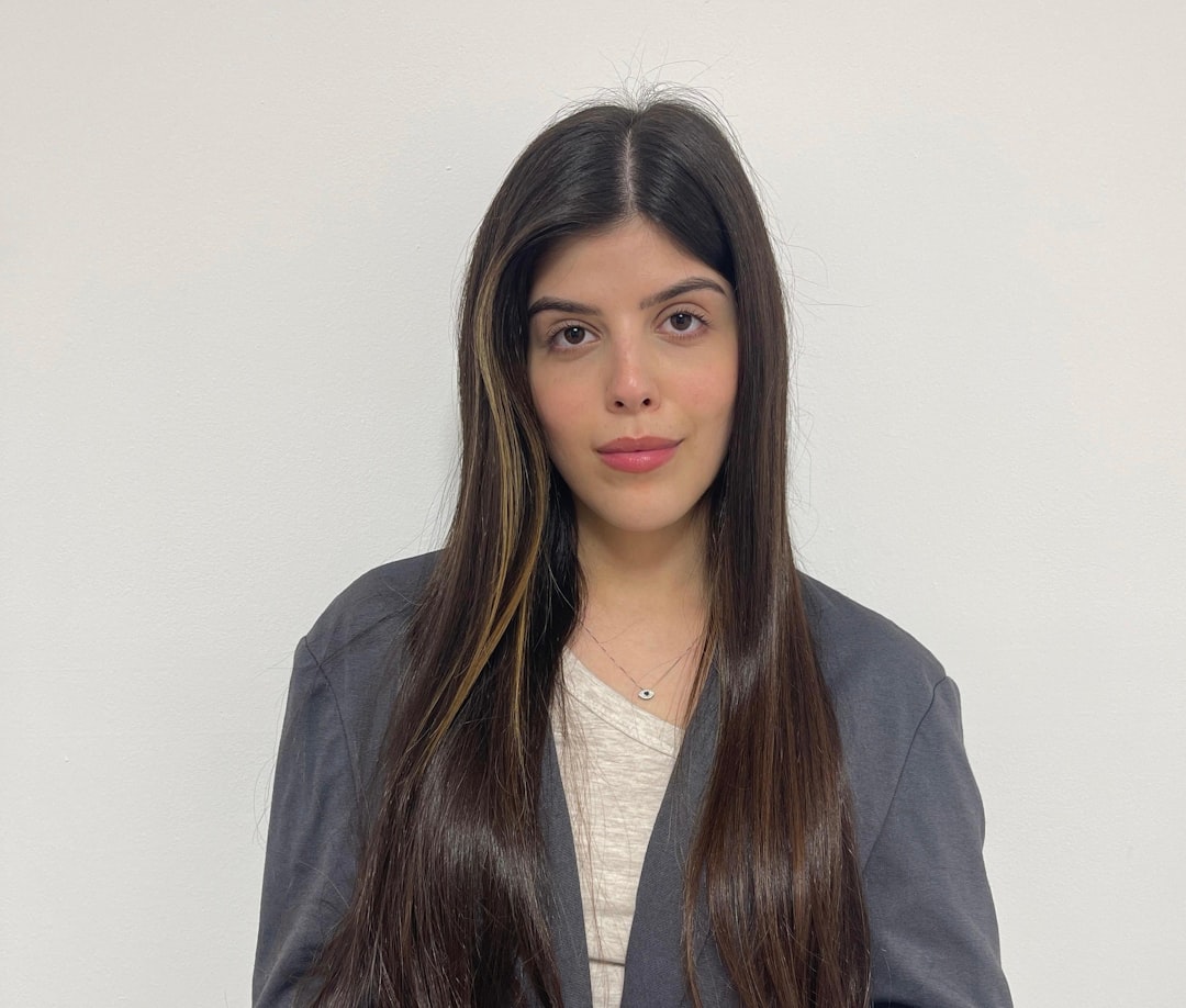 A woman with long hair standing in front of a white wall