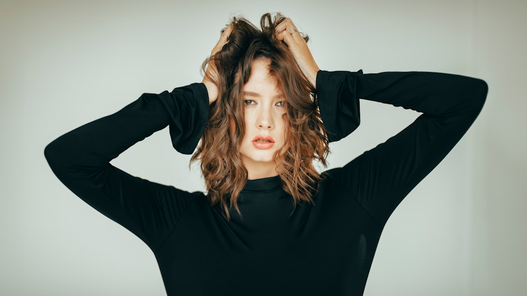 Woman with messy brown hair pulling it