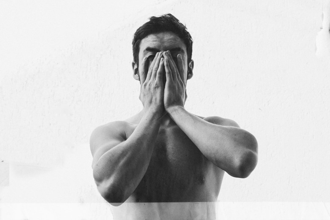 a shirtless man covers his face with his hands