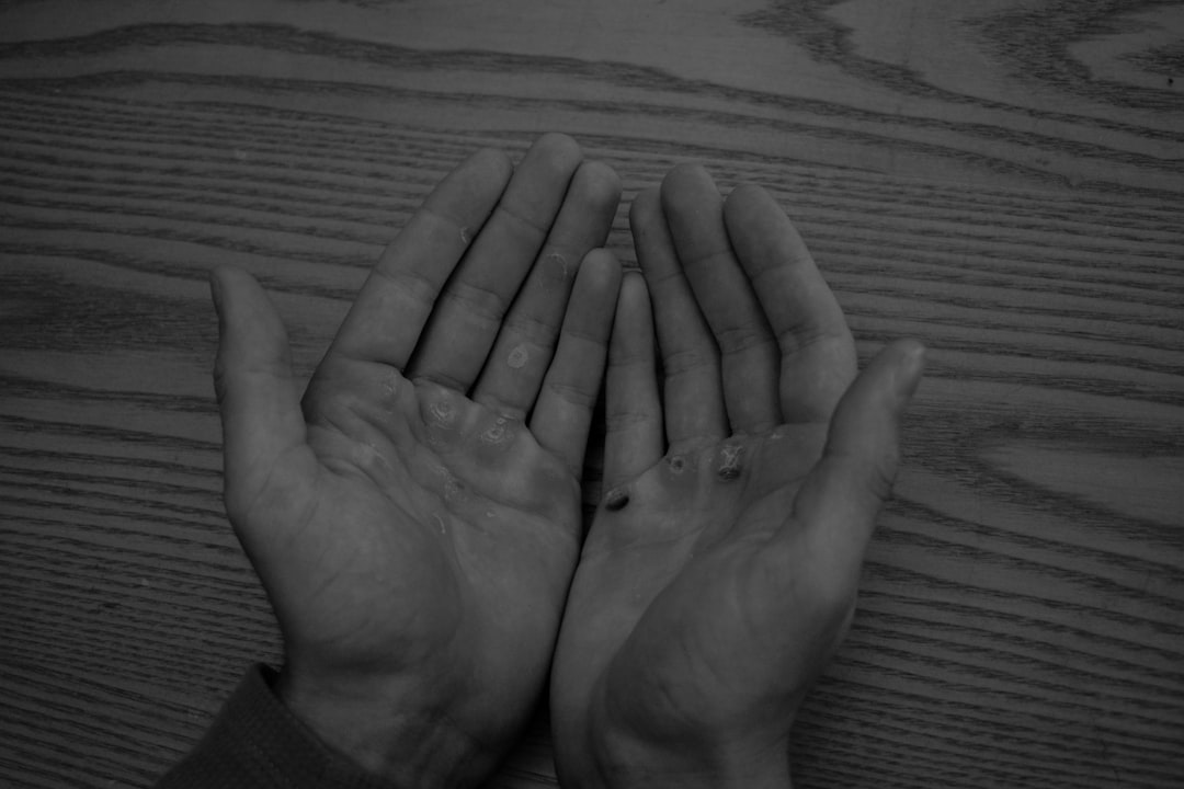 Two hands folded over each other on a wooden table