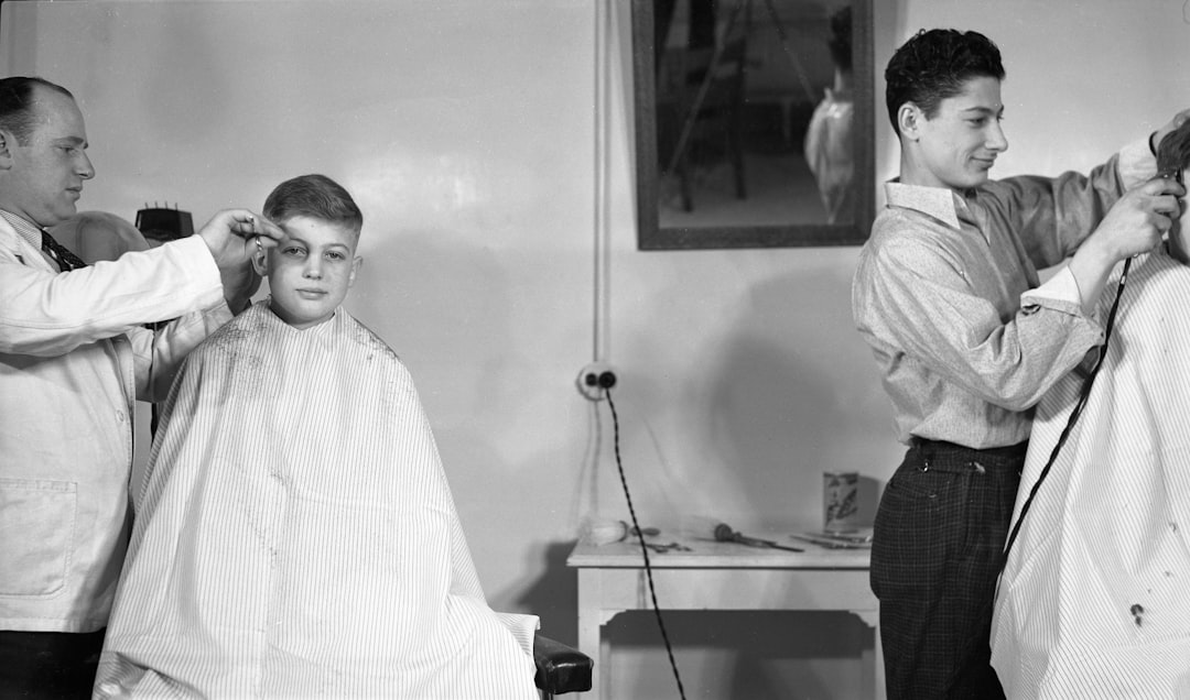 Two barbers giving haircuts to young men