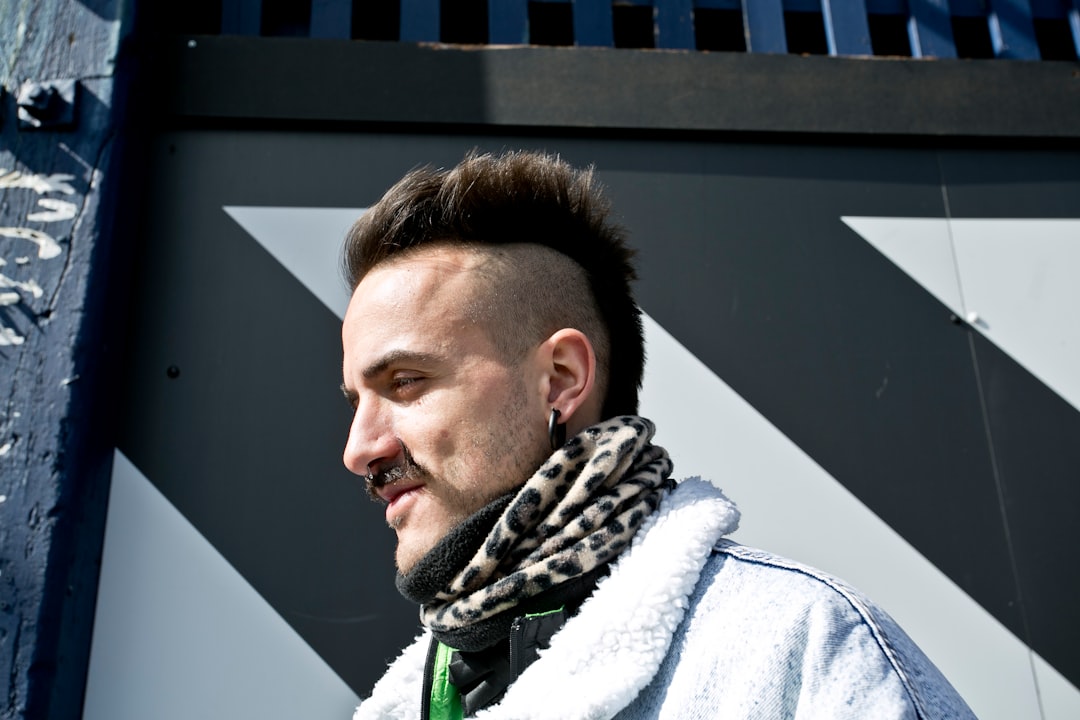 man standing beside white concrete wall