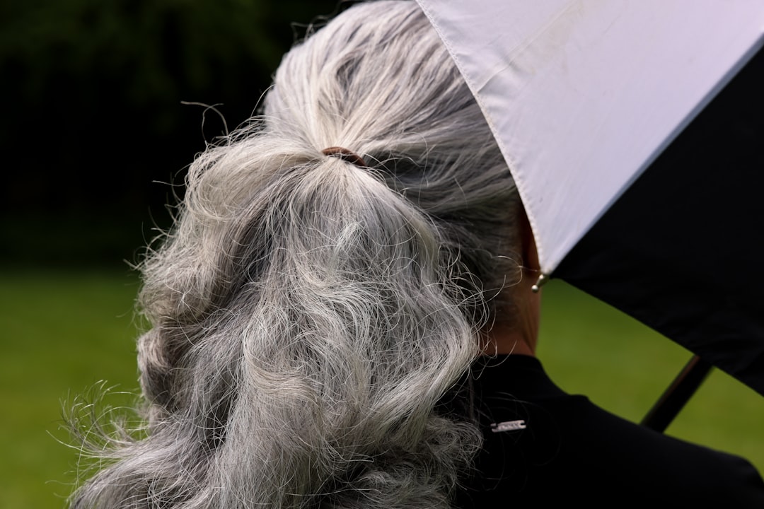 Grey hair is tied back with an umbrella beside it.