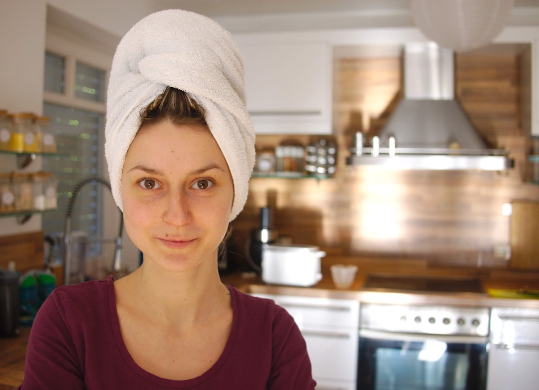 woman in brown crew neck shirt wearing white towel on her head